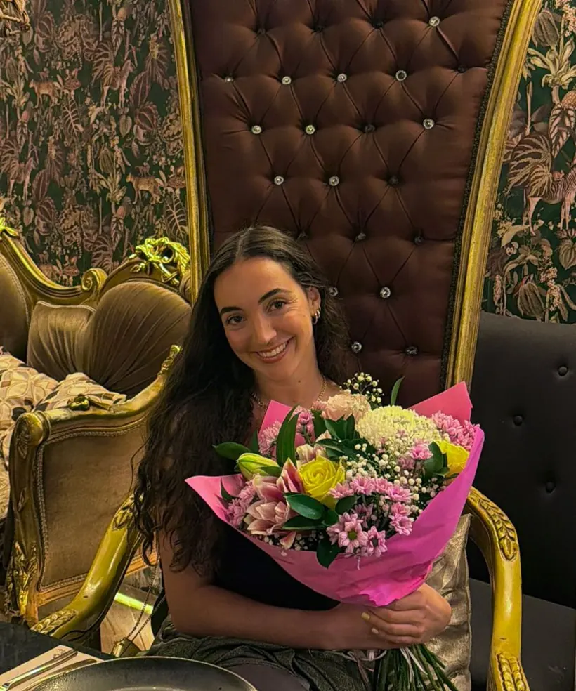 Yeimy González sonriendo con un ramo de flores rosas