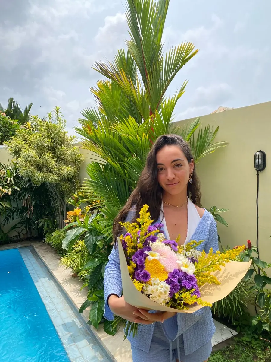 Yeimy González con un ramo de flores en un jardín de Bali